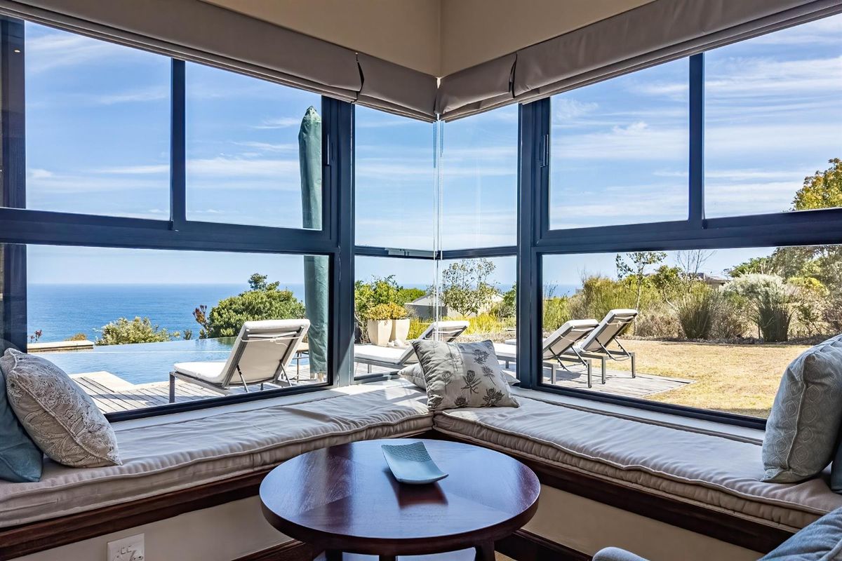 A bright living area featuring a corner window with a built-in window seat, offering expansive views of the pool deck and ocean.