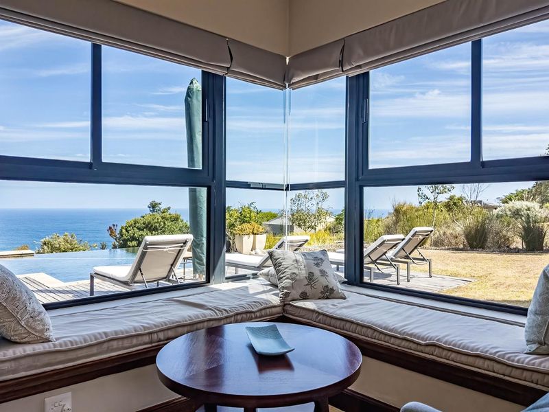 A bright living area featuring a corner window with a built-in window seat, offering expansive views of the pool deck and ocean.