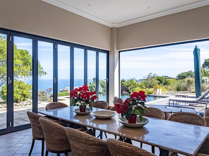 A bright dining area featuring expansive bi-fold doors that open to a patio and pool area, offering scenic ocean views.