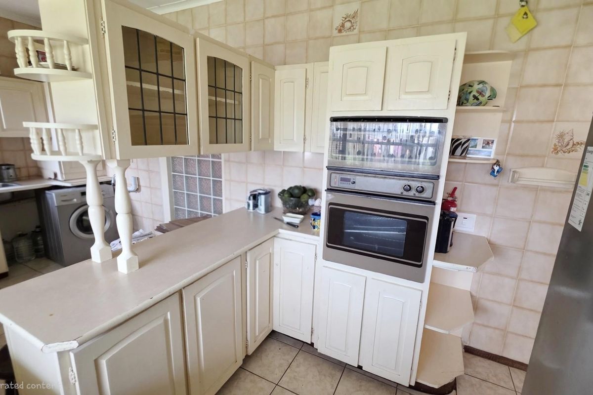 A dated kitchen featuring built-in cabinetry, integrated wall oven, and tiled splashbacks, offering a functional layout with potential for modernization.