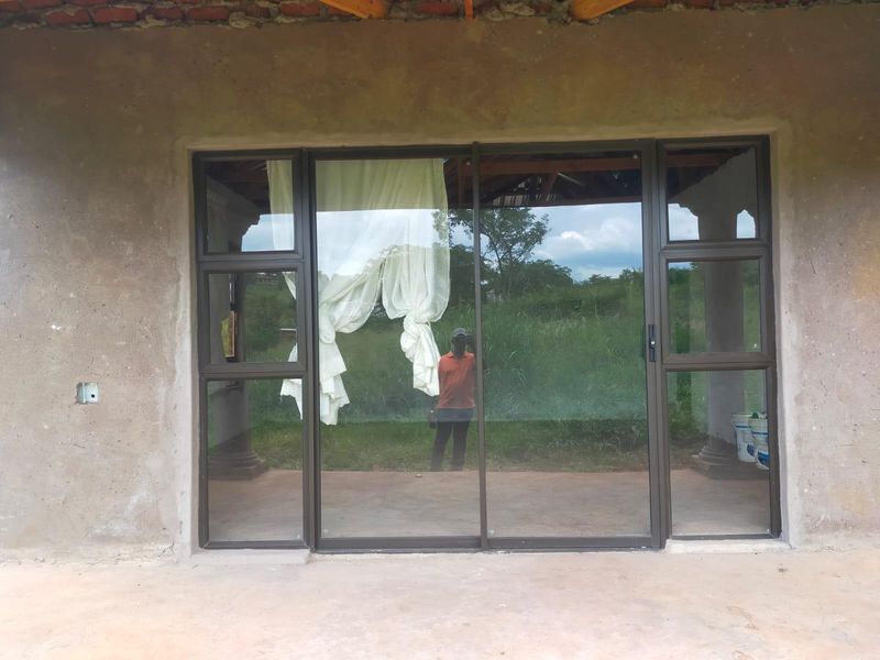 Rear exterior view of a property featuring a sliding glass door set into an unfinished concrete wall with exposed roof rafters.
