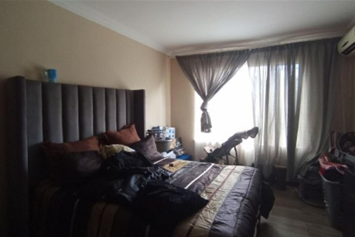 A bedroom featuring a wall-mounted air conditioning unit and crown molding, providing a functional space for rest.