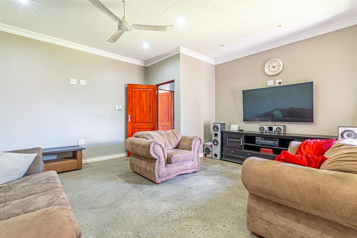 Spacious living room featuring polished concrete flooring, coved cornicing, and a ceiling fan, providing a neutral base for comfortable family living.