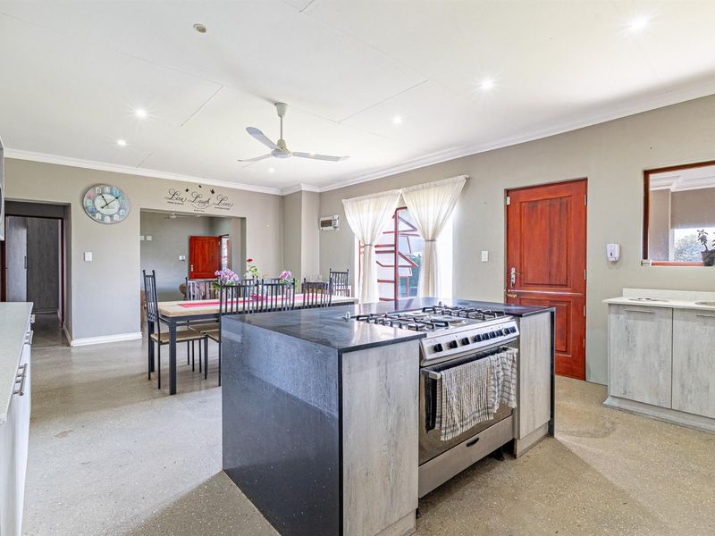 Spacious open-plan kitchen and dining area featuring a central island with gas hob, modern cabinetry, and recessed lighting throughout.