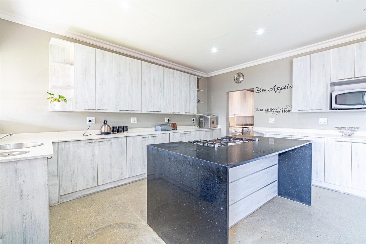 Modern kitchen featuring light wood-grain cabinetry, a contrasting black stone island with a gas hob, and ample counter space.