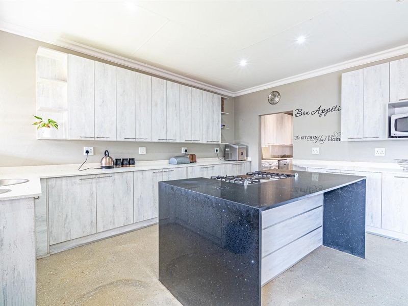 Modern kitchen featuring light wood-grain cabinetry, a contrasting black stone island with a gas hob, and ample counter space.
