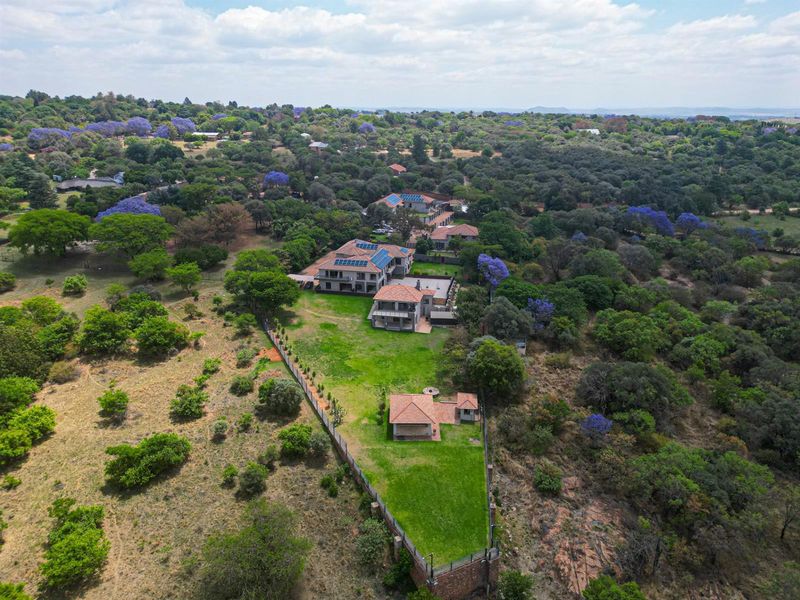 An aerial view of a large residential property featuring multiple buildings, solar panels, and extensive landscaped grounds within a natural bushveld setting.