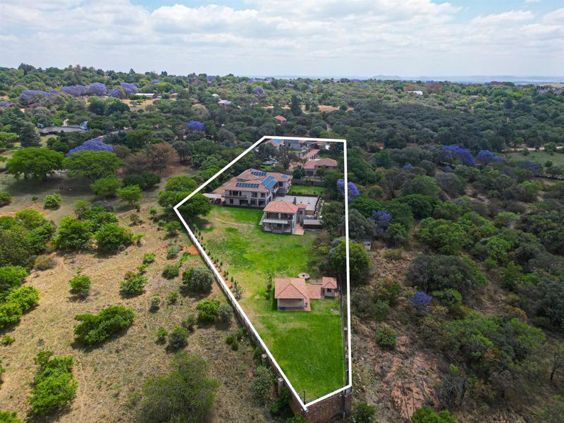 Aerial view of a large residential property featuring multiple buildings, extensive landscaped grounds, and solar panel installations within a defined boundary.