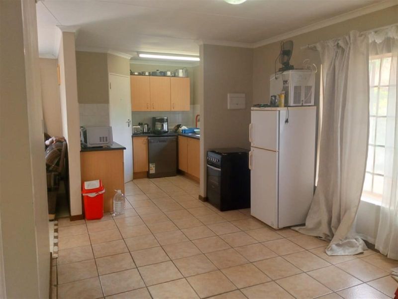 A functional kitchen area featuring tiled flooring, built-in cabinetry, and a dedicated workspace, seamlessly integrated into the open-plan living layout.