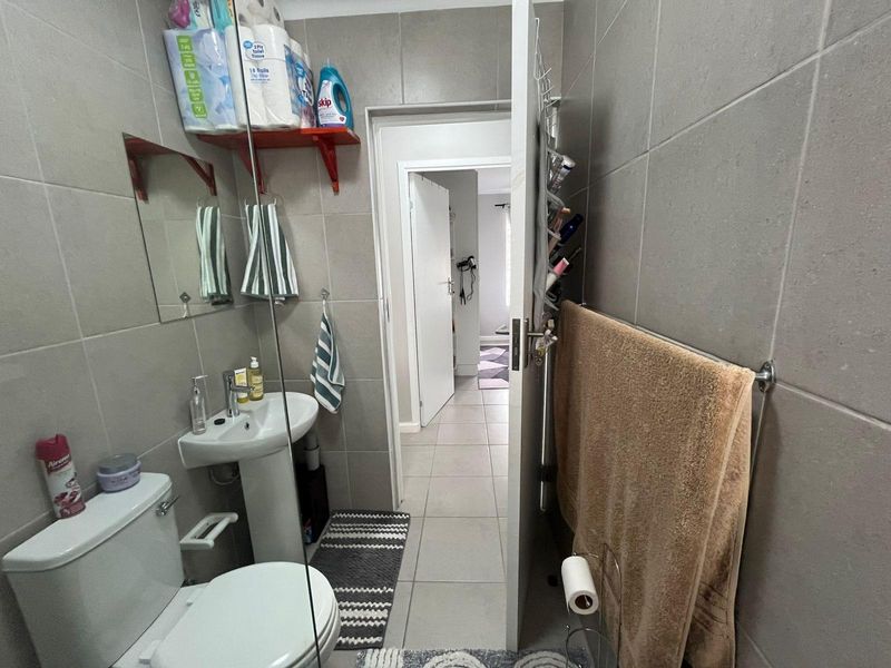 A compact guest bathroom featuring a pedestal basin, toilet, and full-height wall tiling, providing a functional and clean utility space.