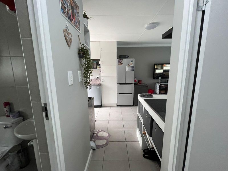 A view from a hallway looking into an open-plan kitchen and living area, with a bathroom visible to the left.