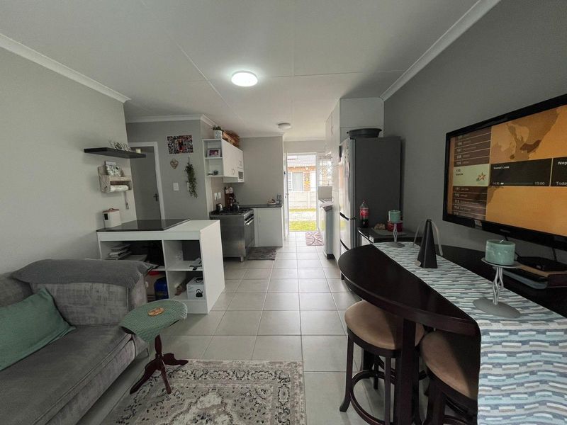 Open plan living and kitchen area featuring tiled flooring, built-in cabinetry, and direct access to the rear exterior.