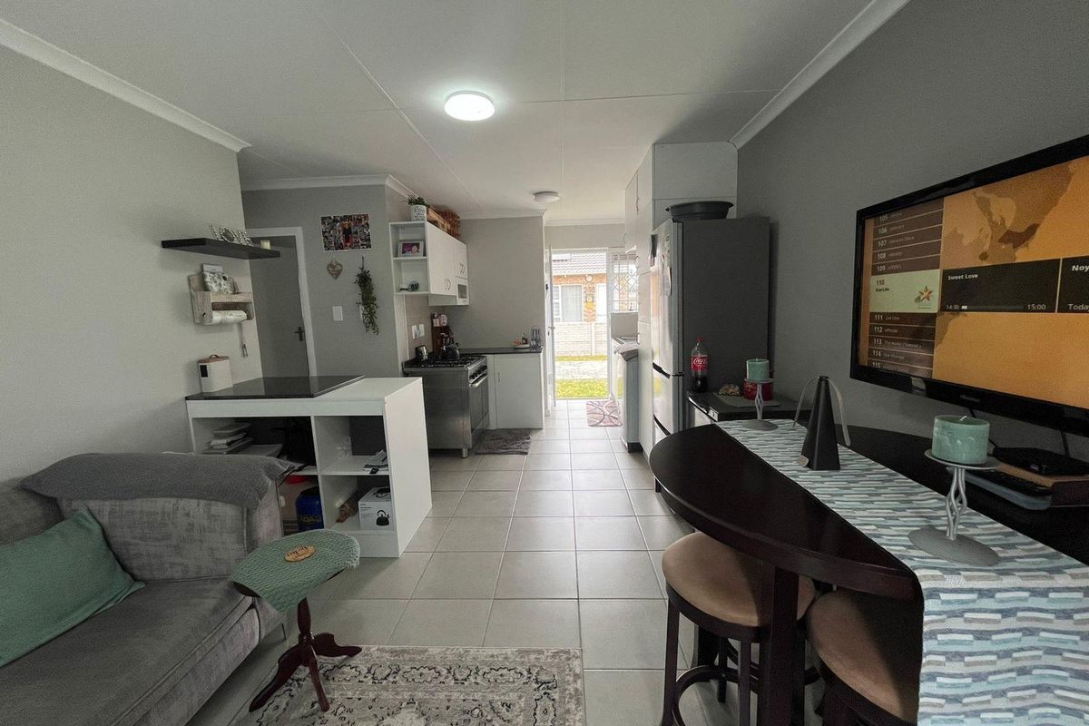 Open plan living and kitchen area featuring tiled flooring, built-in cabinetry, and direct access to the rear exterior.
