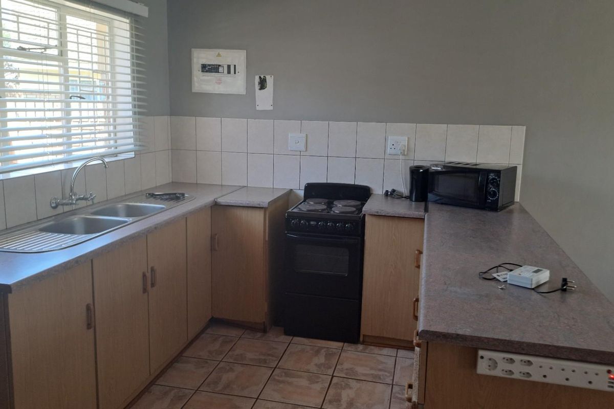 Functional kitchen featuring light wood cabinetry, laminate countertops, double basin sink, and a freestanding stove with tiled splashbacks.