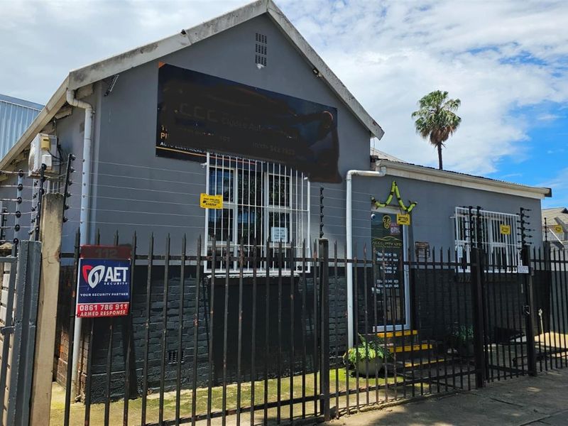 Front exterior view of a commercial office building featuring secure perimeter fencing, electric security wiring, and prominent signage.