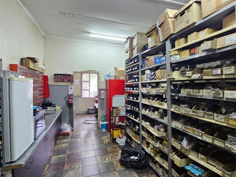 A functional utility or storage space featuring extensive metal shelving units, tiled flooring, and basic cabinetry, suitable for office supply or inventory management.