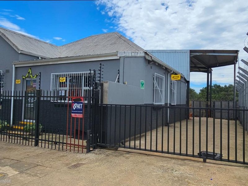 Front exterior view of a commercial office property featuring secure perimeter fencing, electric fencing, and a gated side access area.