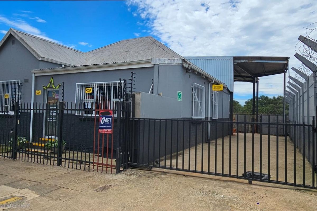 Front exterior view of a commercial office property featuring secure perimeter fencing, electric fencing, and a gated side access area.
