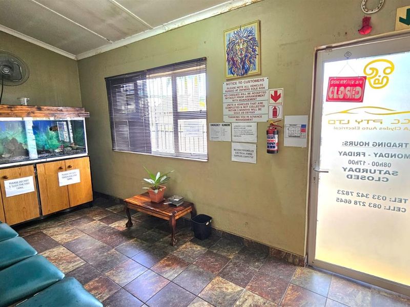 A functional office reception area featuring tiled flooring, a glass entrance door, and wall-mounted signage.