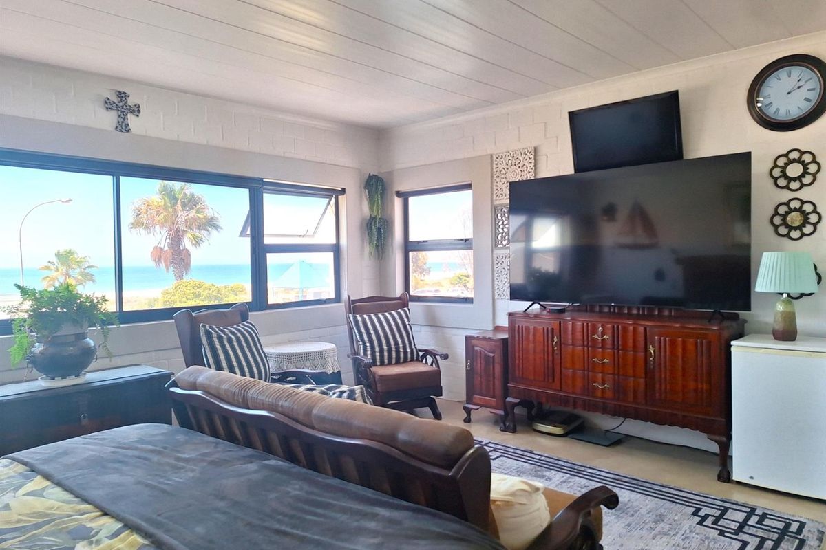 A living room featuring large windows with ocean views, painted brick walls, and a tongue-and-groove ceiling.