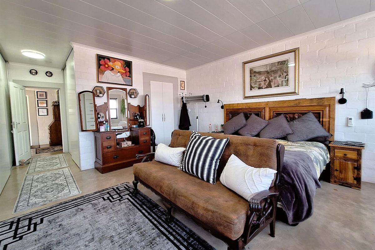 Spacious bedroom featuring painted brick walls, tiled flooring, and built-in storage, offering a functional layout with direct access to the hallway.