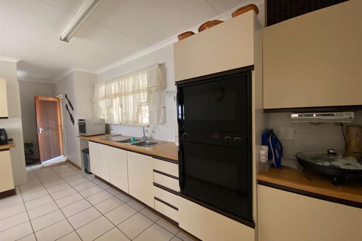 Functional kitchen featuring built-in oven, double sink, laminate countertops, and tiled flooring, offering a practical layout with ample storage space.