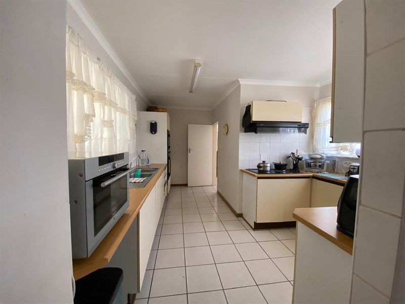 A functional kitchen featuring tiled flooring, built-in cabinetry, laminate countertops, and integrated appliances including an oven and hob.