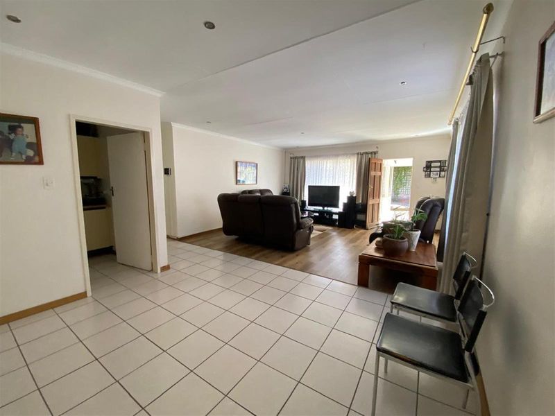 Spacious open-plan living area featuring a combination of tiled and laminate flooring, recessed lighting, and direct access to the outdoor space.