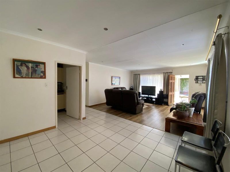 Spacious open-plan living area featuring a combination of tiled and laminate flooring, recessed downlights, and direct access to the outdoor patio.