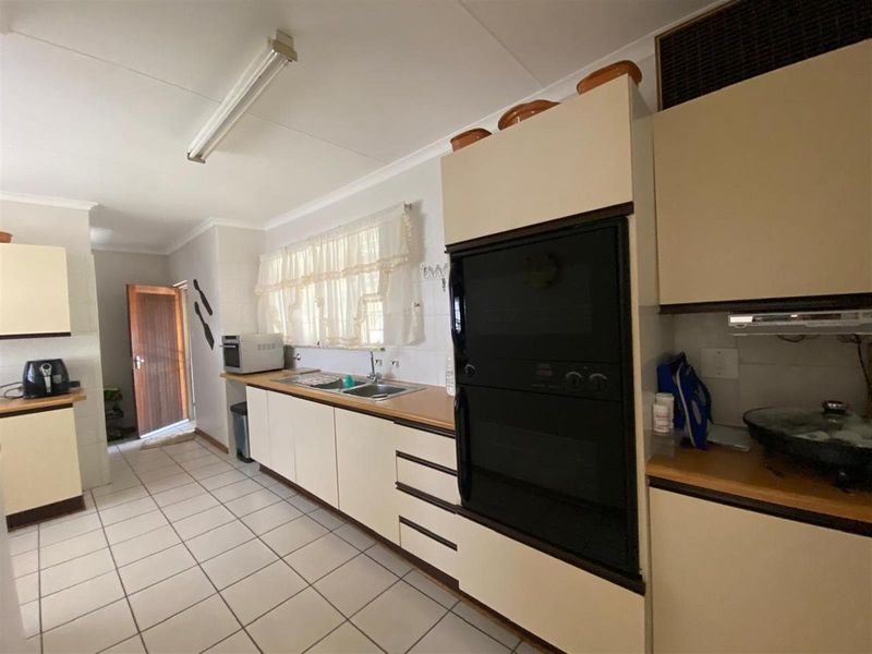A functional kitchen featuring built-in cabinetry, a double sink, laminate countertops, and a built-in oven, with tiled flooring throughout.
