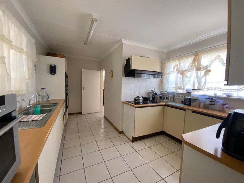 Functional kitchen featuring laminate countertops, built-in oven, electric hob, extractor fan, and tiled flooring with ample storage cabinetry.