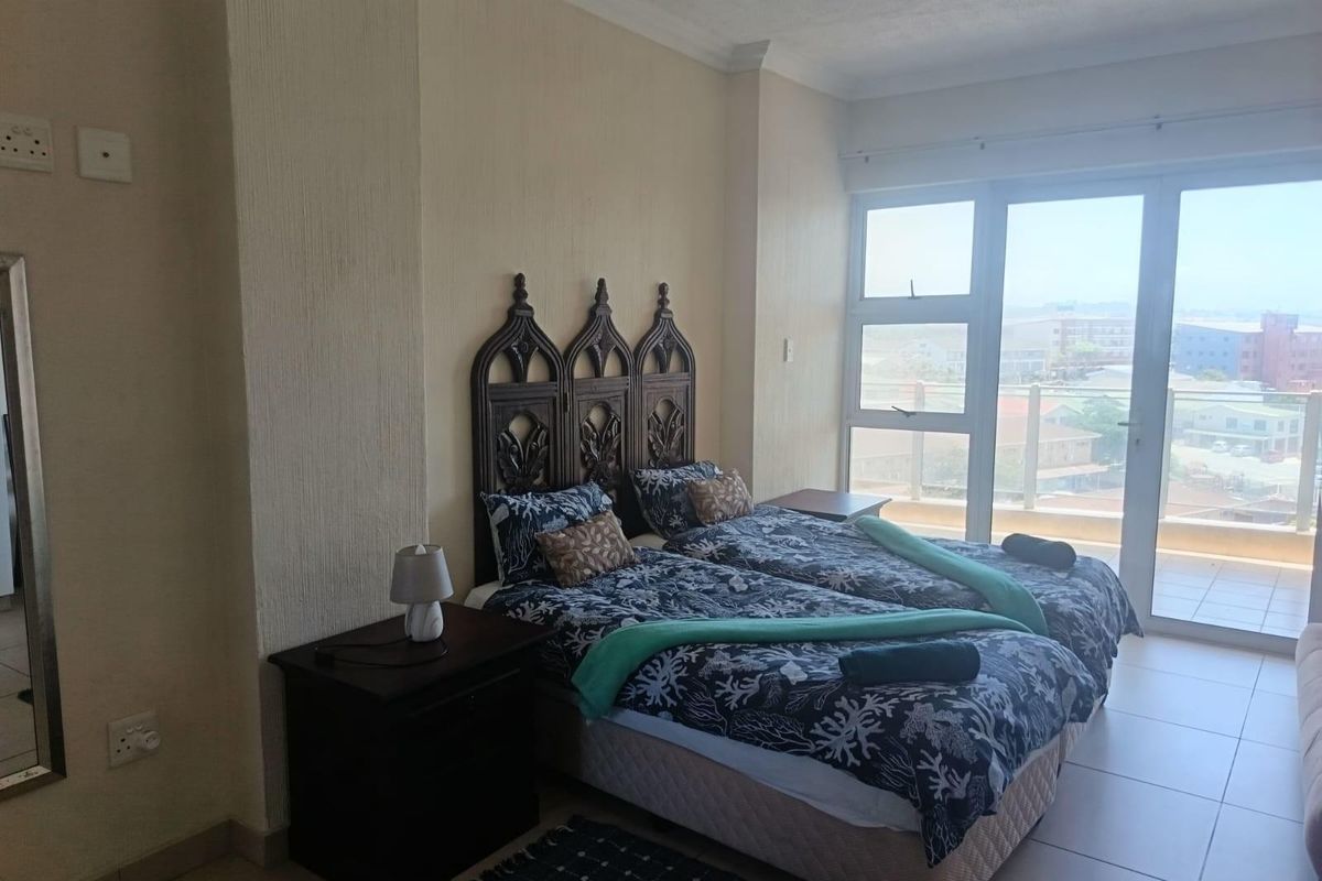 A bedroom featuring tiled flooring and large sliding glass doors that provide access to a balcony and offer natural light.