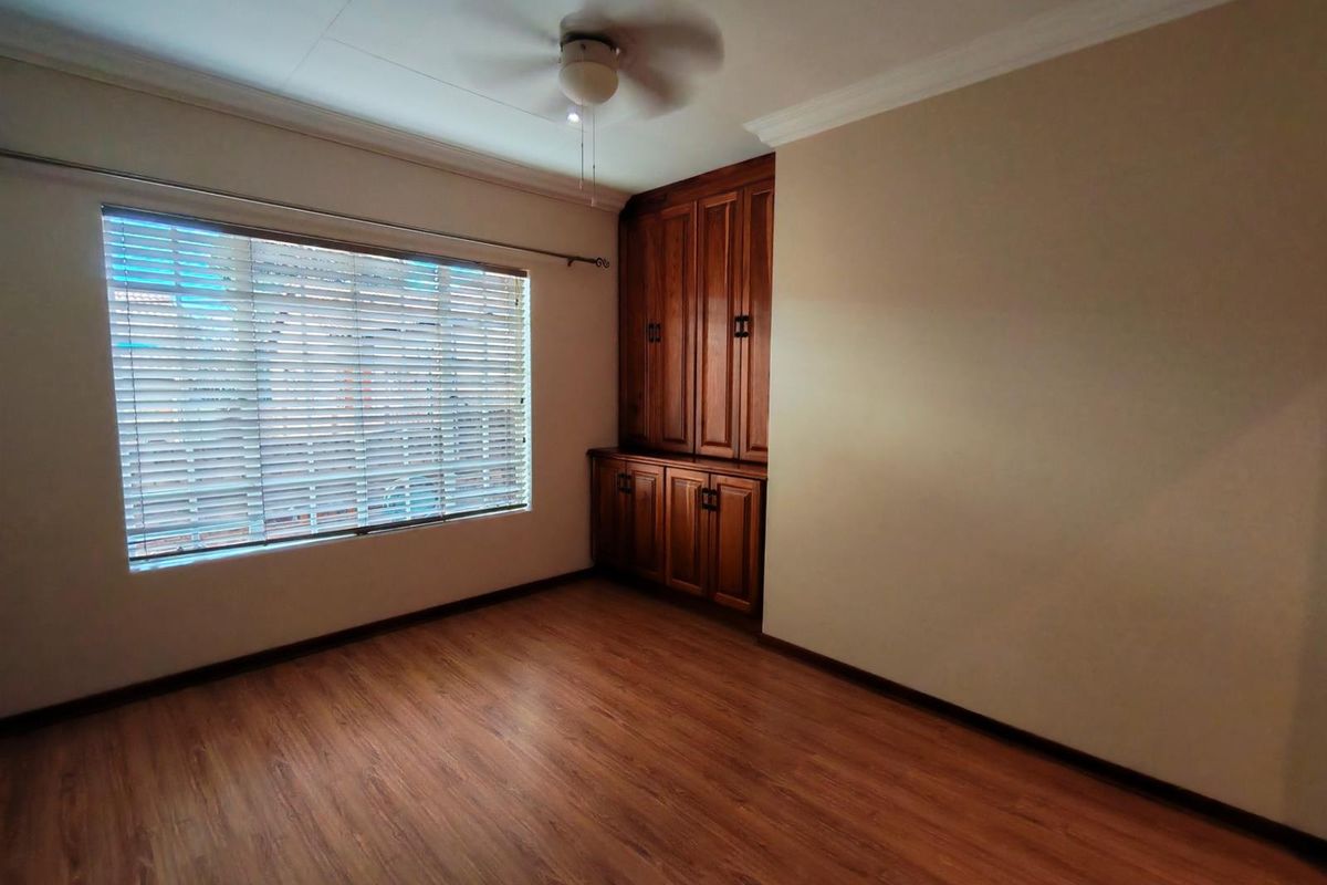 A bedroom featuring wood-look laminate flooring, a ceiling fan, and built-in wooden cabinetry.