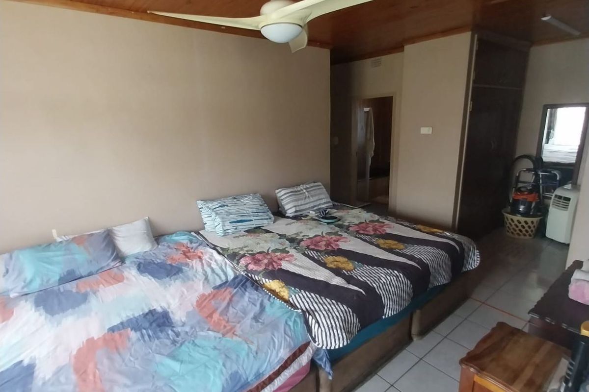 A bedroom featuring a timber-clad ceiling, ceiling fan, tiled flooring, and built-in cupboard storage.