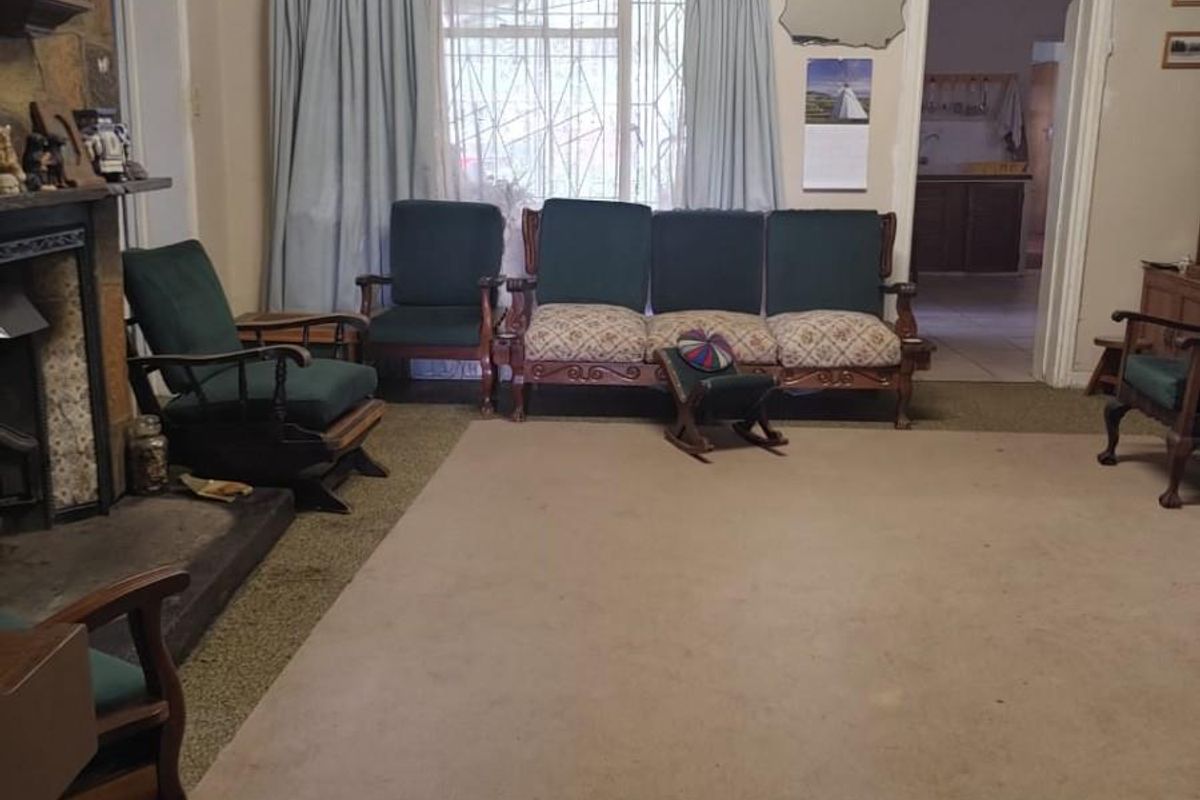 A living room featuring a stone fireplace and carpeted flooring, offering a traditional layout with access to adjacent rooms.