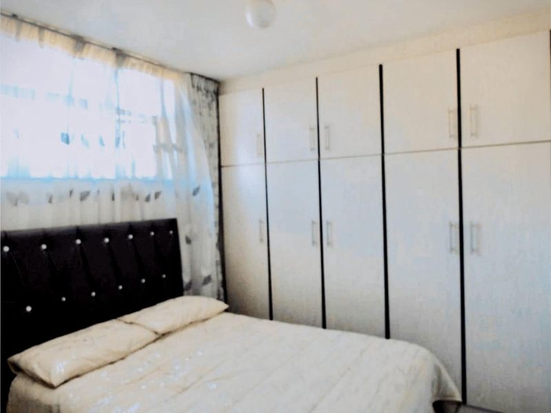 A bedroom featuring floor-to-ceiling built-in cupboards providing ample storage space.