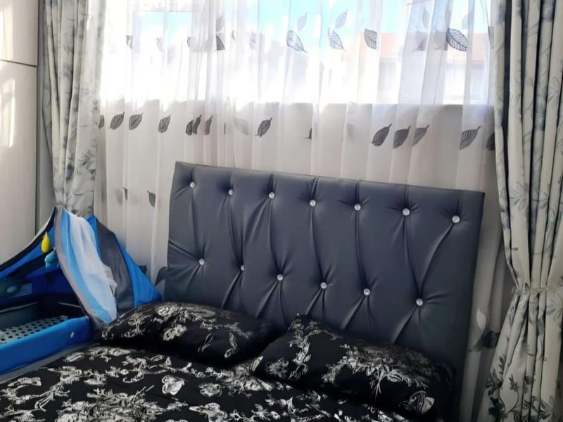 A bedroom featuring a large window with curtains and a built-in wardrobe, providing natural light and storage space.