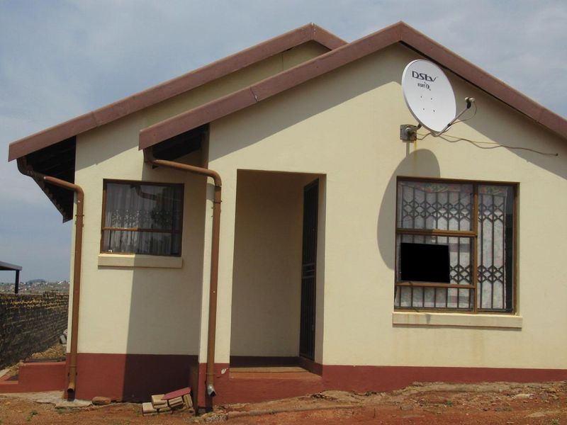 Front elevation of a detached house featuring a plastered facade, guttering, security bars on windows, and a satellite dish installation.