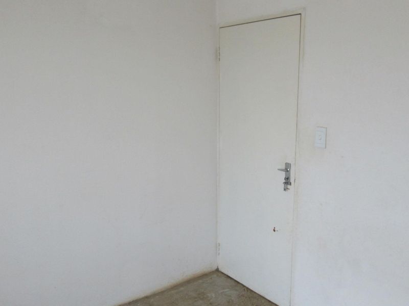 An empty room featuring a plain internal door and basic light switch, requiring cosmetic updates to the walls and flooring.