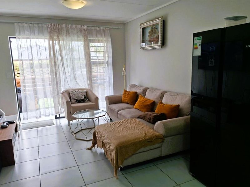 A living room featuring tiled flooring and a sliding glass door providing access to the outdoor area.