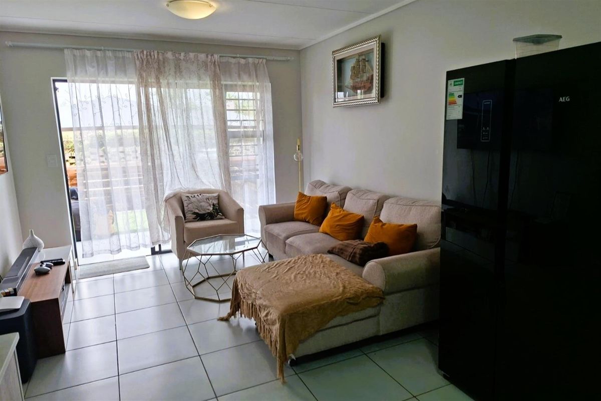 A living room featuring tiled flooring and a sliding glass door providing access to the outdoor area.