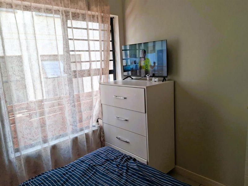 A bedroom featuring a window with integrated security bars, providing natural light and ventilation.