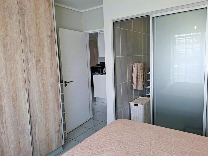 Bedroom featuring built-in wooden cabinetry, a sliding door wardrobe, and tiled flooring, with a view into an adjacent room.