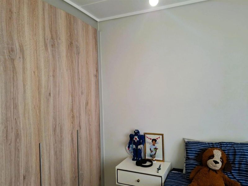 A bedroom featuring a modern wood-grain finish built-in wardrobe and neutral wall tones.