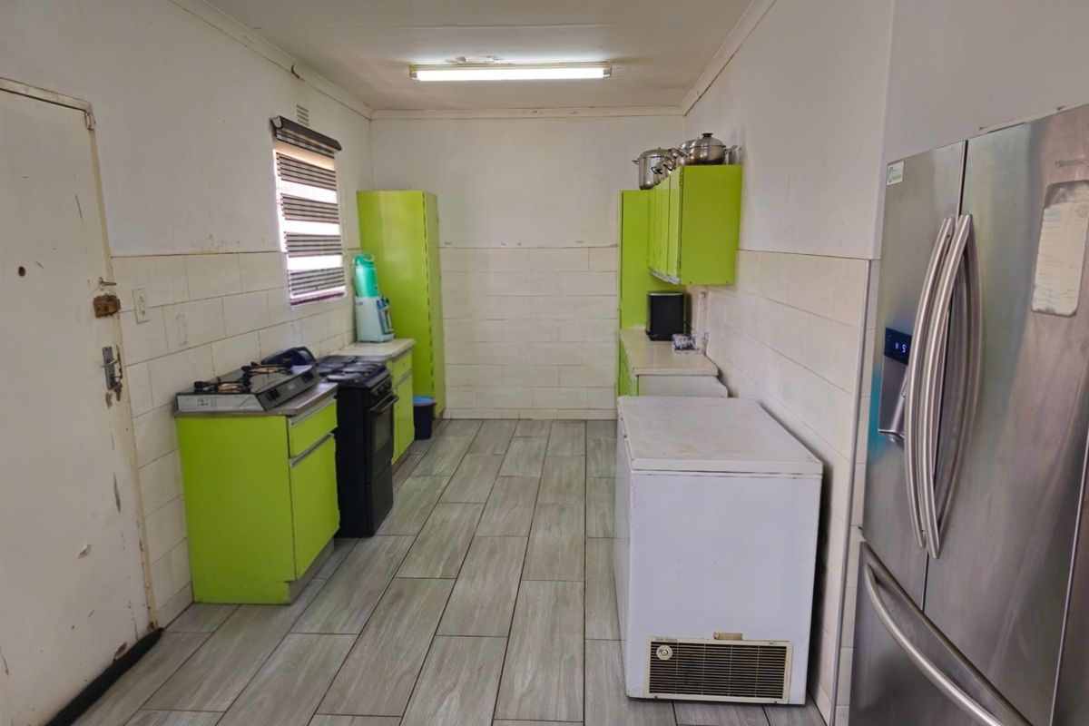 A functional kitchen space featuring lime green cabinetry, tiled flooring, and built-in stove, offering a practical layout for culinary activities.