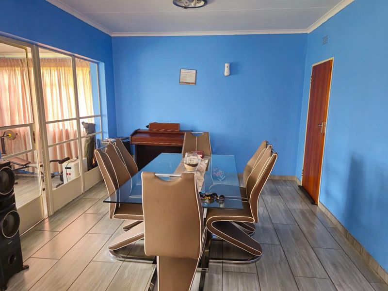 A dining room featuring tiled flooring, blue painted walls, and a glass-paneled sliding door leading to an adjacent space.