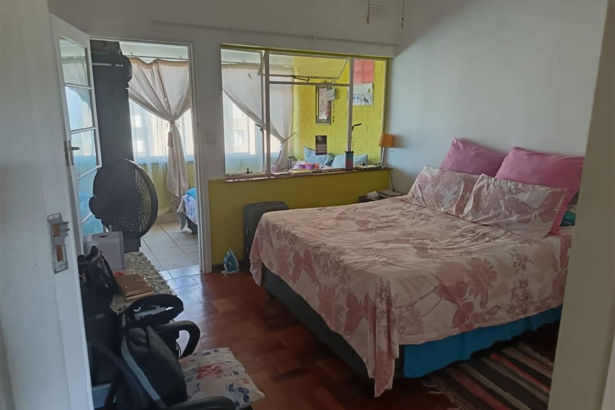 Bedroom featuring parquet flooring and an internal window connecting to an adjacent sunroom or balcony area.