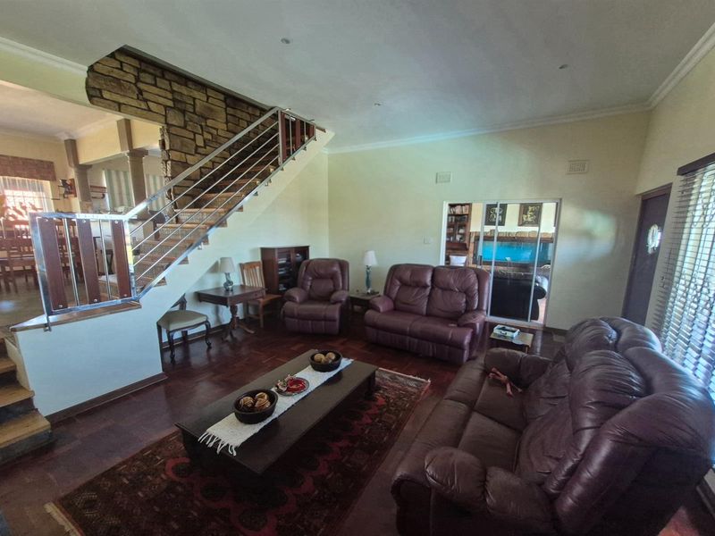 Spacious open-plan living area featuring a prominent stone-clad staircase with stainless steel balustrades and dark wood flooring.