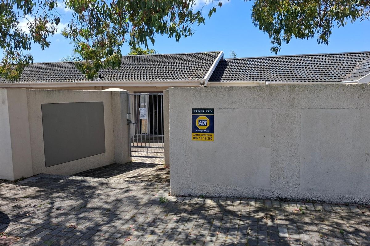 Front entrance view of the office property featuring a secure gated access point, perimeter wall, and tiled roof structure.