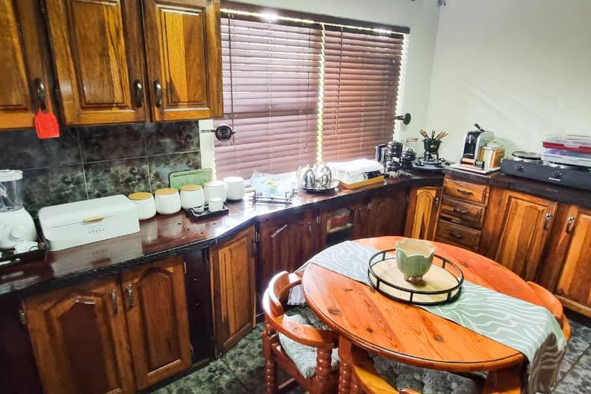 A functional kitchen featuring traditional timber cabinetry, dark stone countertops, tiled splashbacks, and a dedicated breakfast nook area.